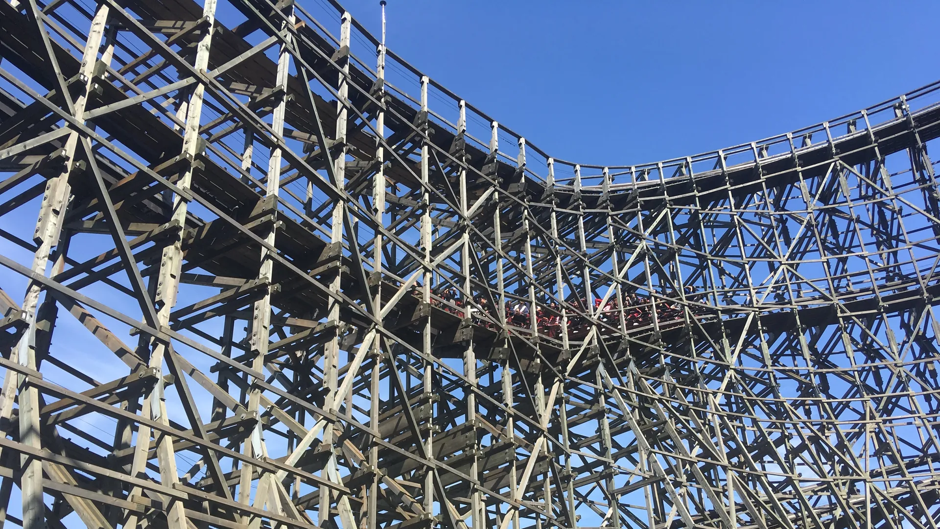 The tall wooden lattice of the park's T Express roller coaster curving against a clear blue sky
